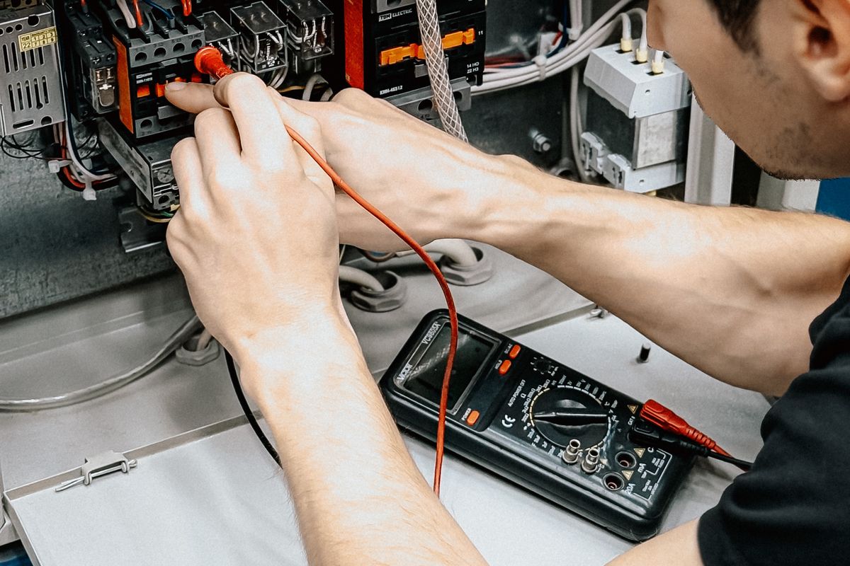 A technician testing an electrical panel with a multimeter